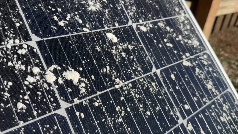 Close-up view of a solar panel covered with dust and debris, indicating the need for cleaning and maintenance